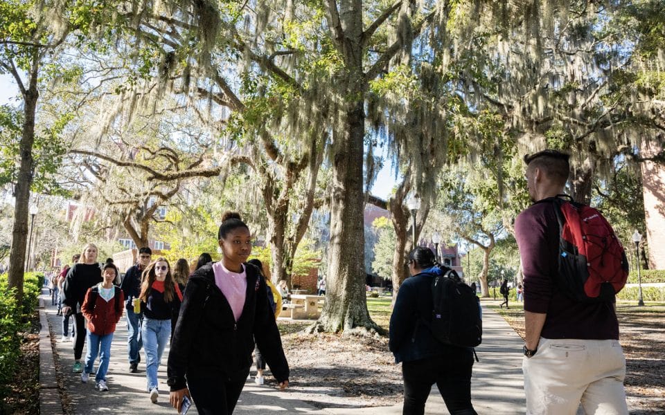 Campus scene of multiple students walking along a sidewalk