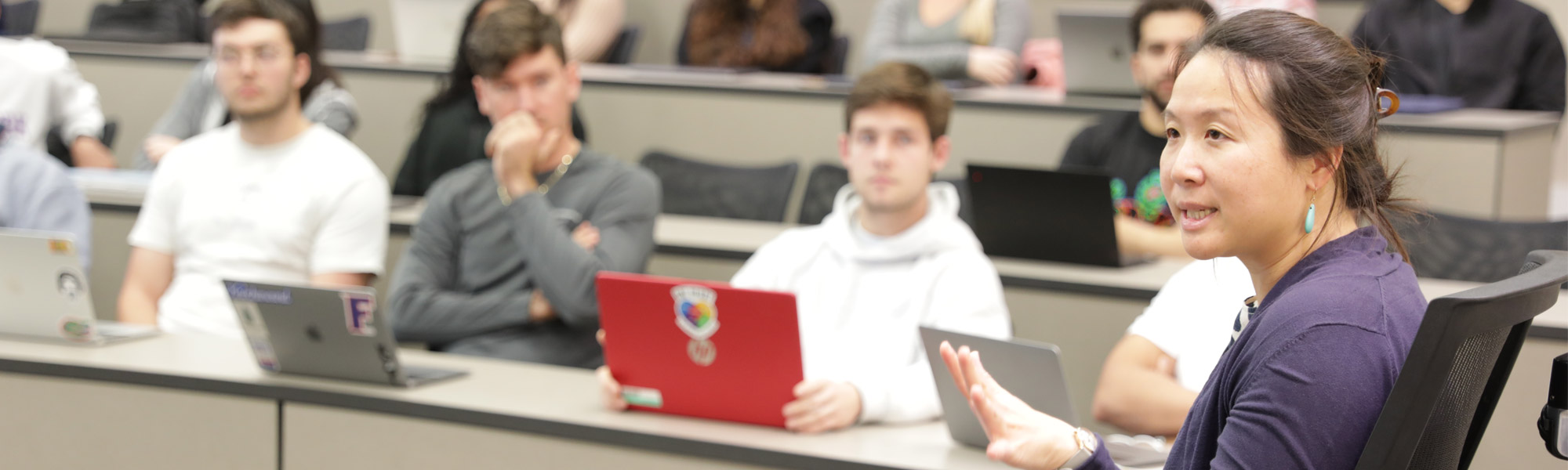 Students look on as a woman speaks in class