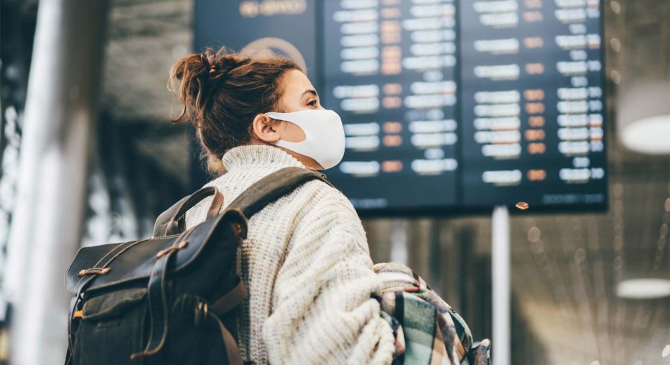 Young woman wearing a mask traveling through an airport or train station