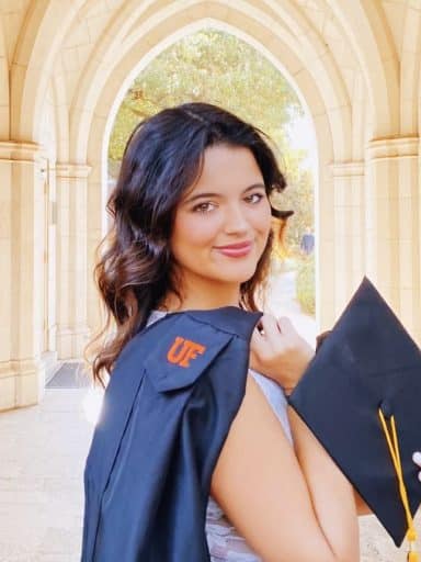 Alexia Dauelsberg with a graduation cap and gown on the UF campus