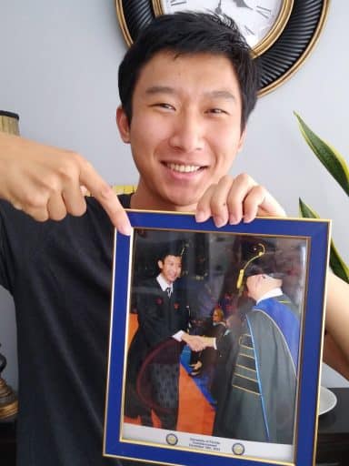 Avery Fu holds a photo of himself shaking hands with Saby Mitra at his graduation