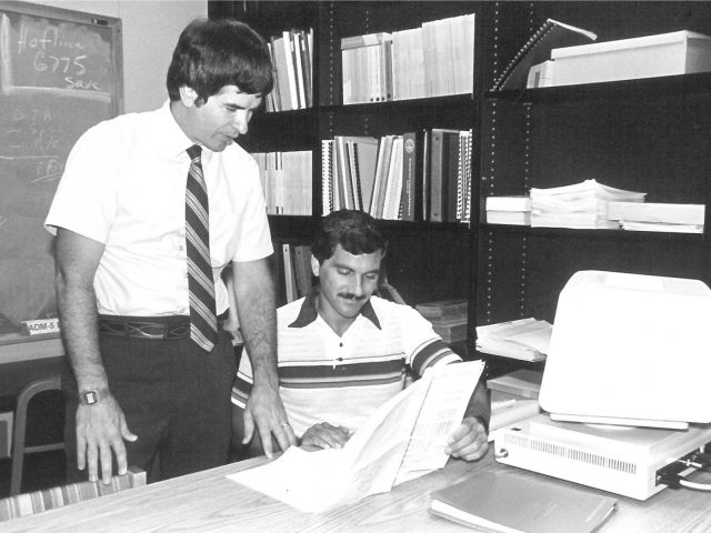 Wayne Archer and a colleague at a desk in a black and white photo