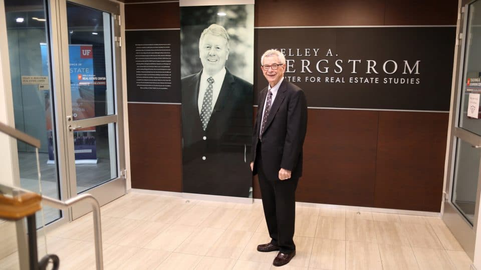 Wayne Archer by the Bergstrom Center entrance with Kelley Bergstrom's portrait and Center name on the wall behind him