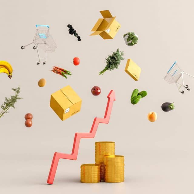 Groceries, shopping carts and boxes float in the air above an upward trending arrow and stacks of gold coins