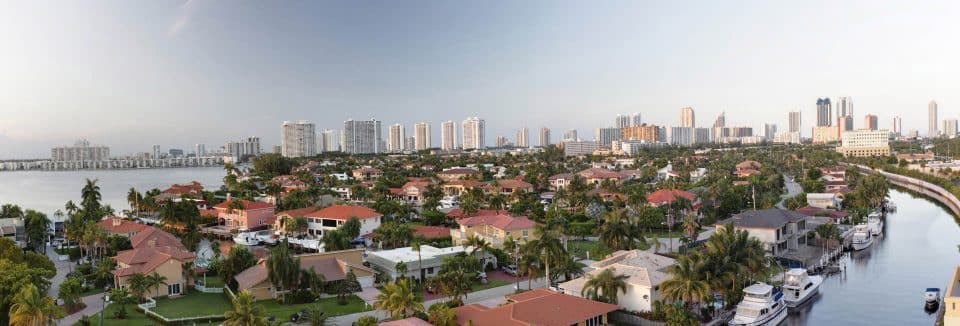 A florida neighborhood borders the water on two sides with city skyline in the background