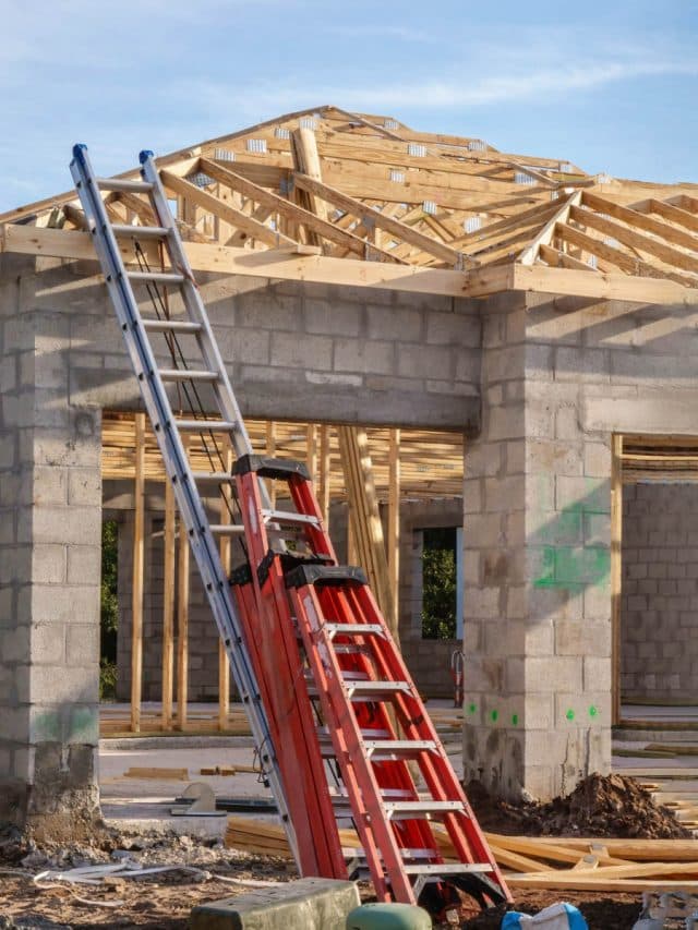 Construction of a home with block walls as ladders lean against the side
