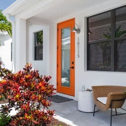 A white home with an orange front door in Odyssey by Soltura