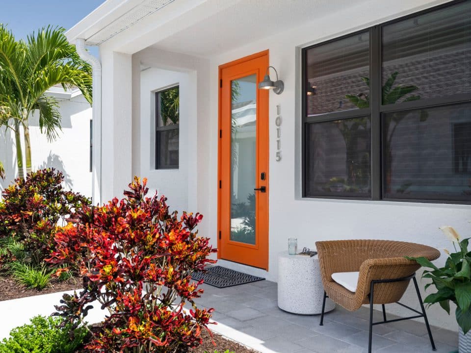 A white home with an orange front door in Odyssey by Soltura