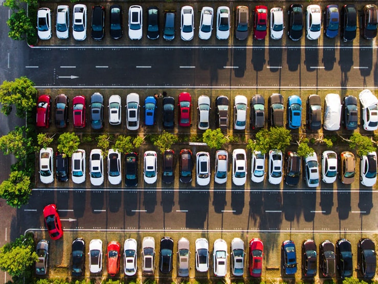An aerial view of a parking lot with many cars and only one empty parking spot