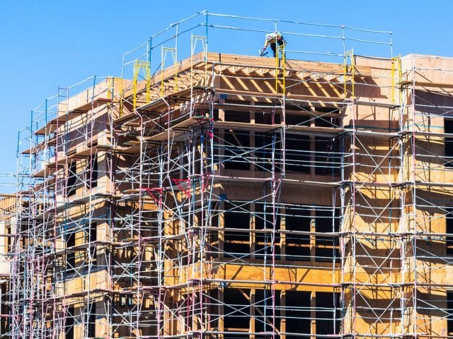 A construction worker on top of a residential building surrounded by scaffolding in Sunnyvale, California