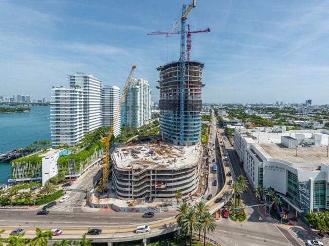 A tall building under construction near the water in Miami-Dade County