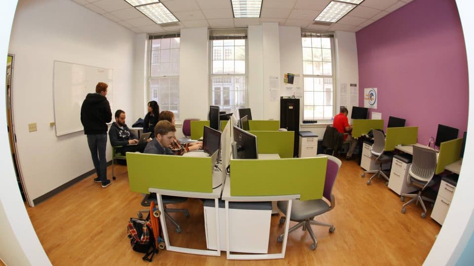 Students work at stations with computers in the incubator for the Entrepreneurship and Innovation Center