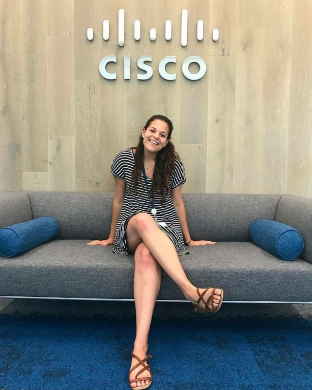 Gabriella Tedesco sits in front of a wall with the Cisco logo on it