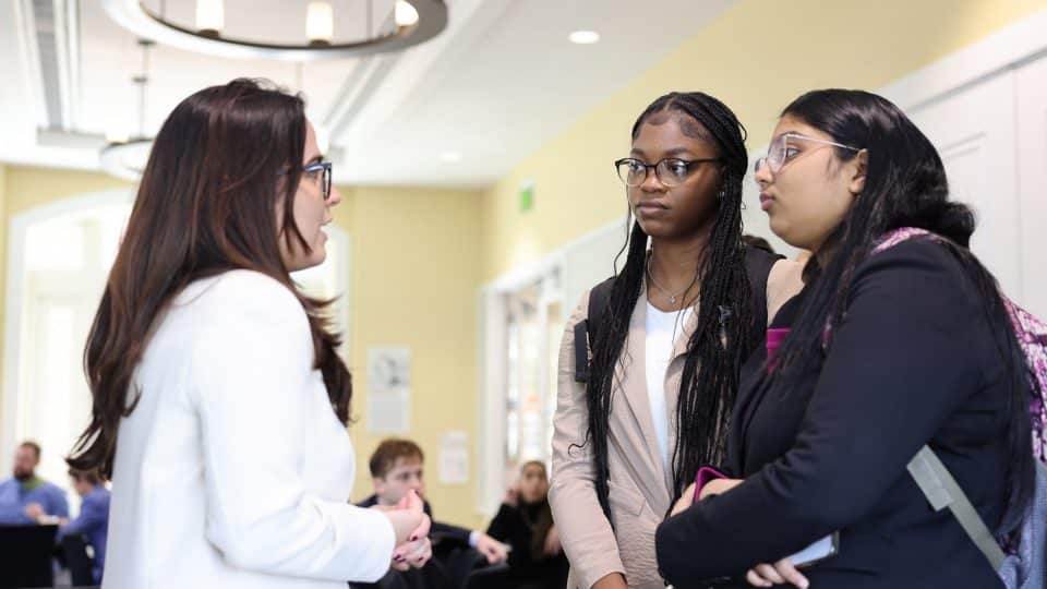 Two students talk with a recruiter at an event
