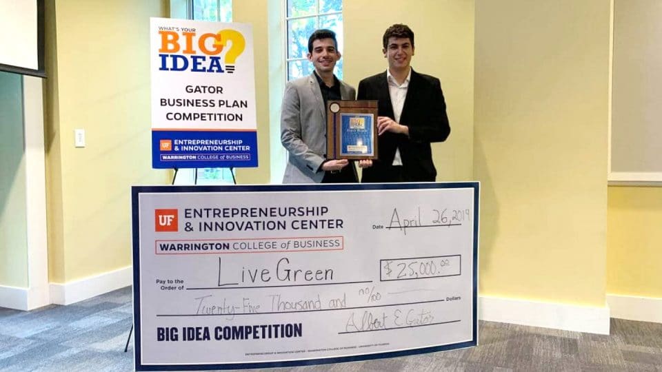 Two students accept the award and $25,000 check for the Big Idea Gator Business Competition Plan