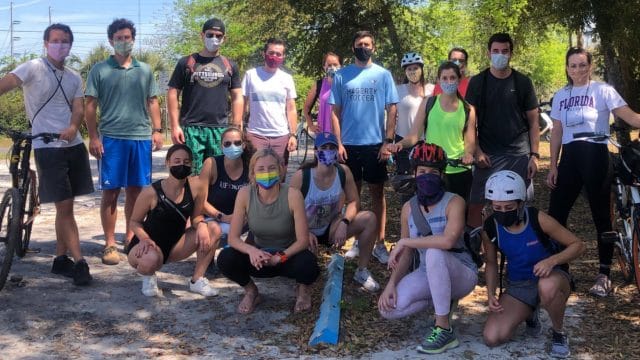 Group of students assembled outside with masks, some with bikes and bike helmets for the Murph Challenge they participated in