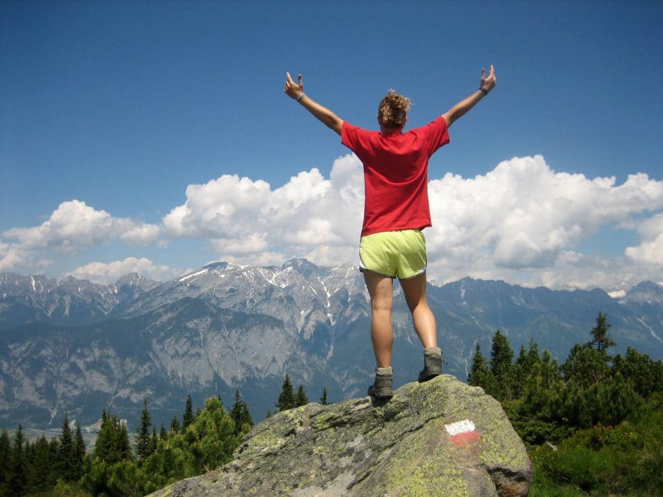 Young woman with arms stretched upward as she gazes upon the Mountain scenery near Innsbruck, Austria