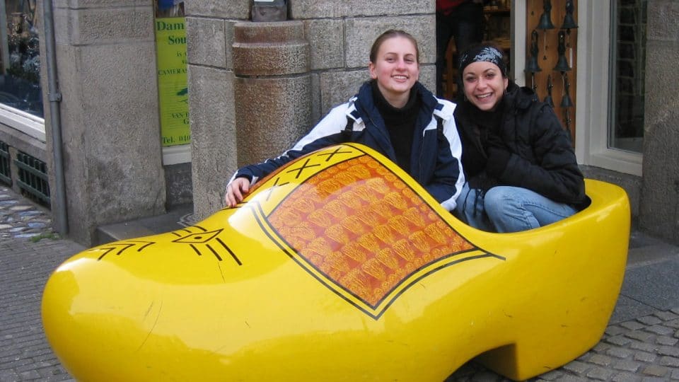 Two young women sit in a giant yellow clog in Amsterdam, Netherlands
