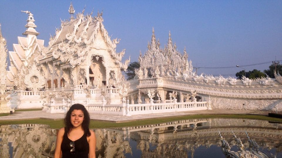 Young woman stands before the White Temple in Thailand