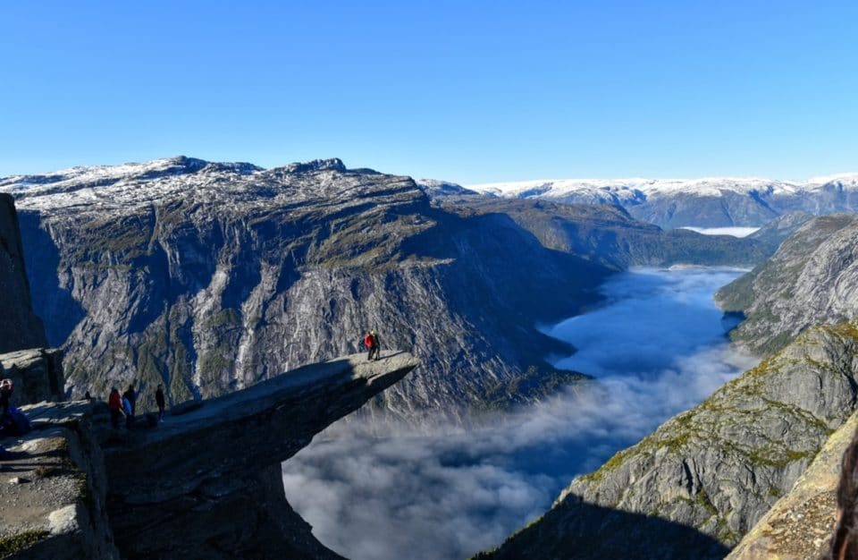 Student on cliff overlooking mountains and water in Norway