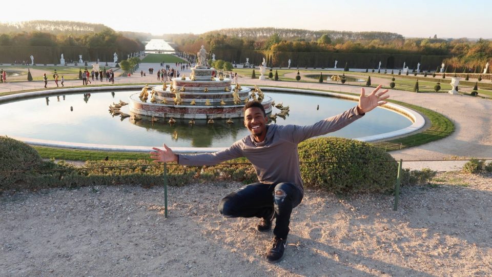 Student in front of fountain at Versailles Palace in Paris, France.
