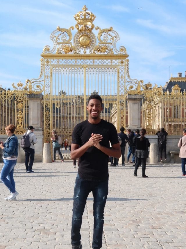 Student in front of gate at Versailles Palace in Paris, France.