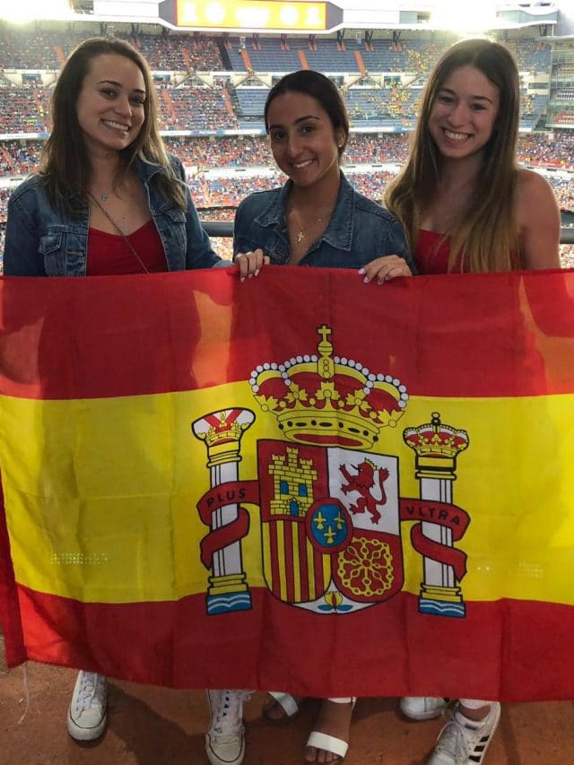 Three students holding flag of Spain in Bernabeu Stadium in Madrid, Spain.