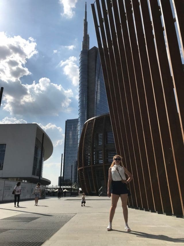 Student standing in front of skyscraper in Milan, Italy