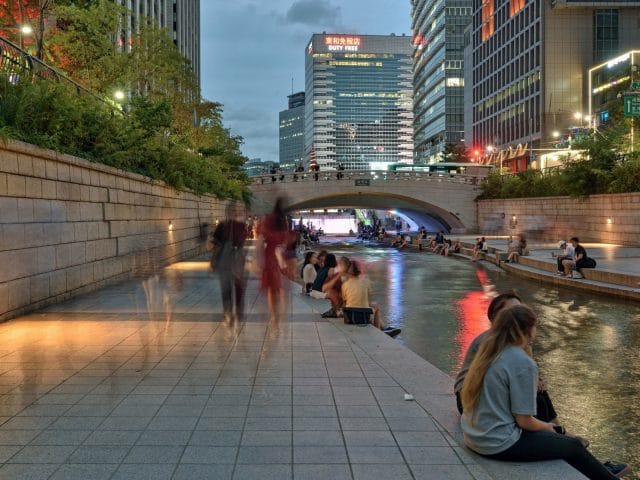People enjoy an evening walking and sitting along the Cheonggyecheon River in downtown Seoul, South Korea