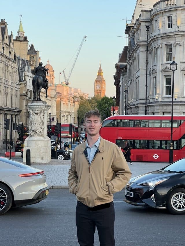 Student ambassador, Samuel, in London in front of a red bus and Big Ben.